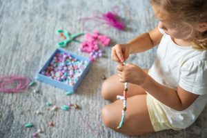 little girl making a friendship bracelet