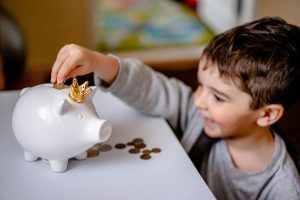 Kid putting money in his piggy bank